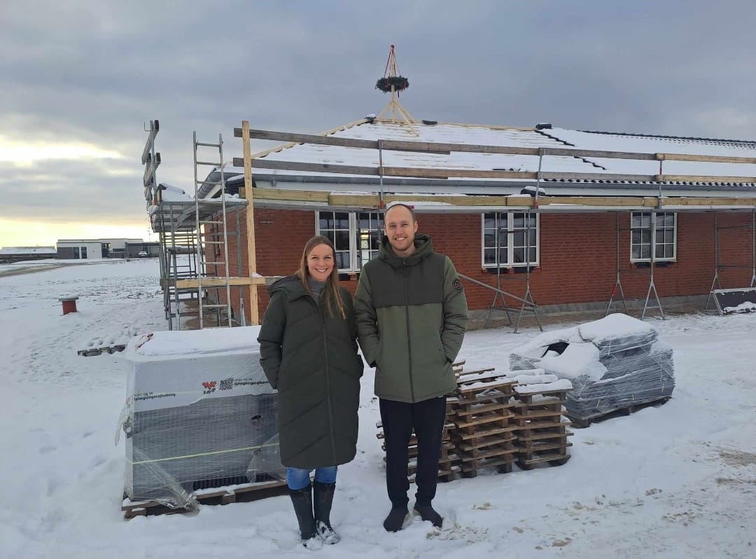 Par foran nybygget hus i snevejr