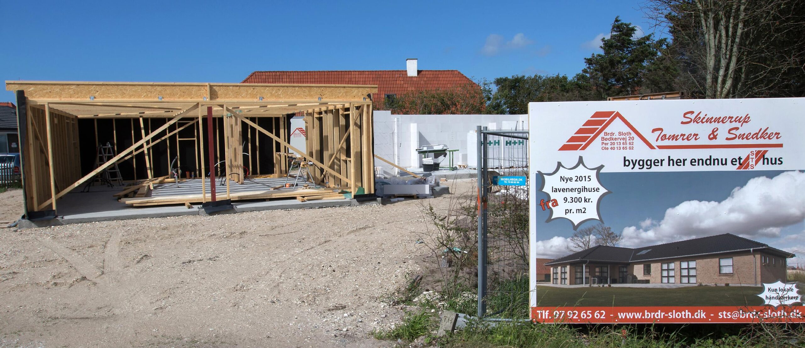 Hus under opførelse med træskelet og byggeskilt