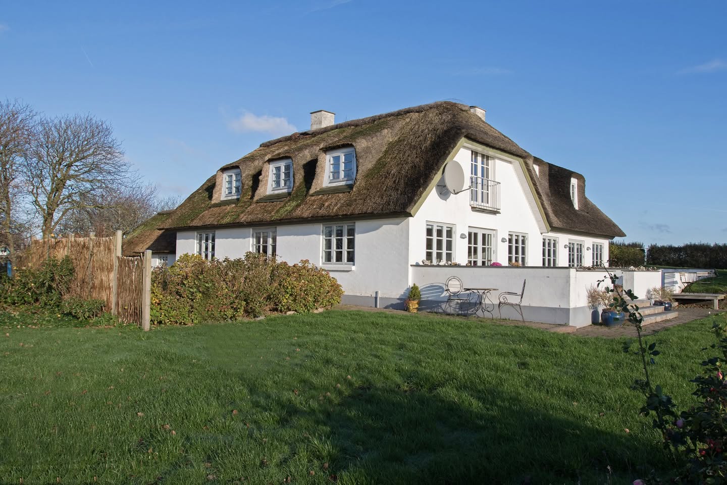 Hvidt hus med stråtag og grøn have