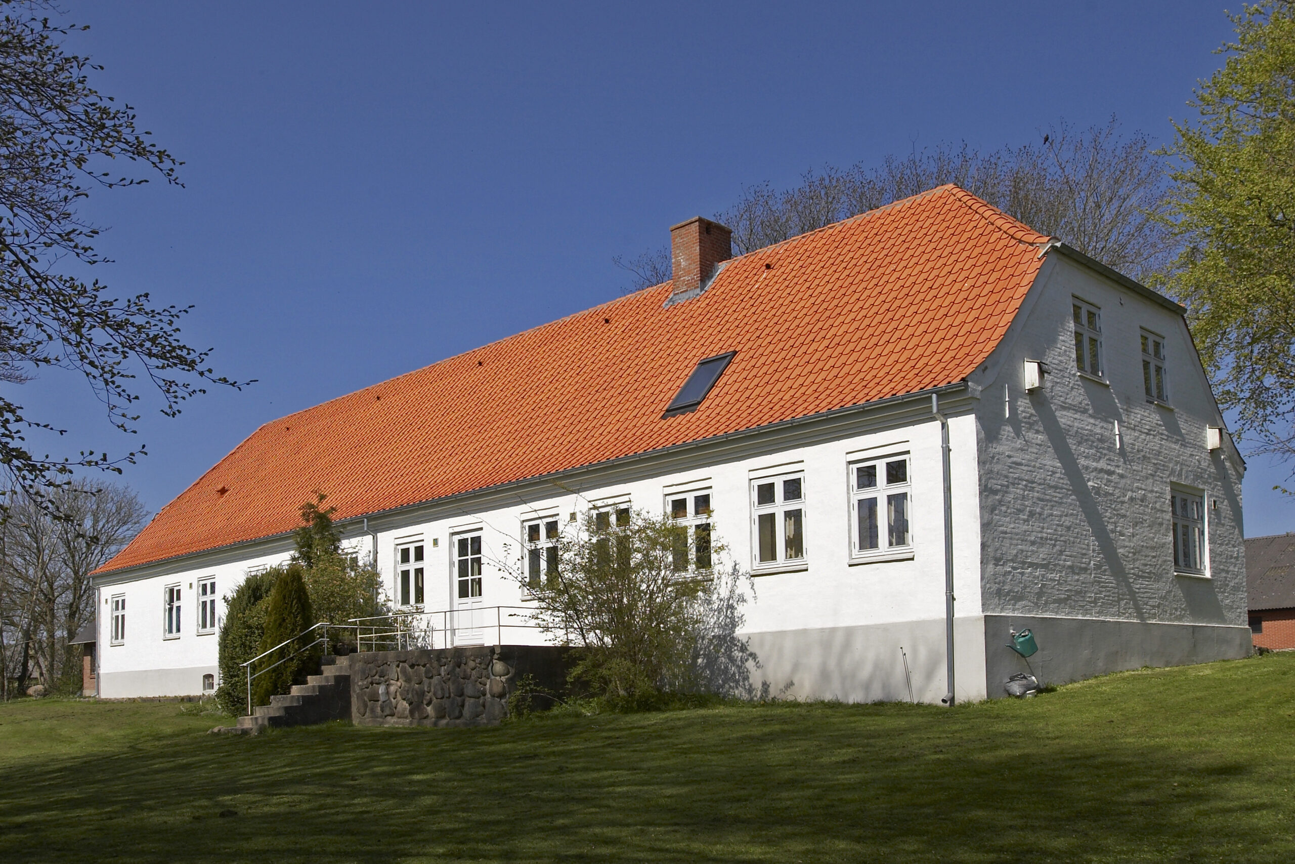 Hvidt hus med orange tegltag på landet