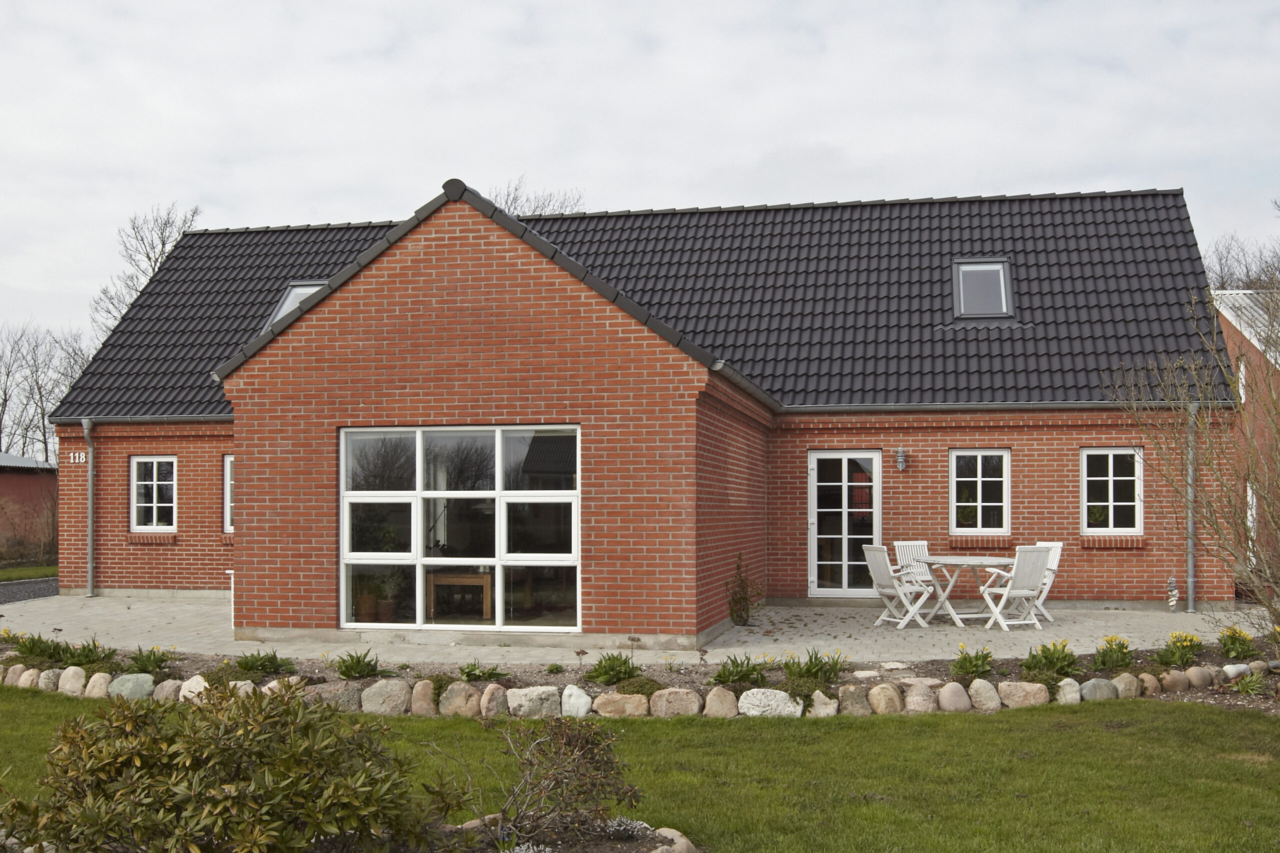 Moderne rødstenshus med sort tegltag og terrasse