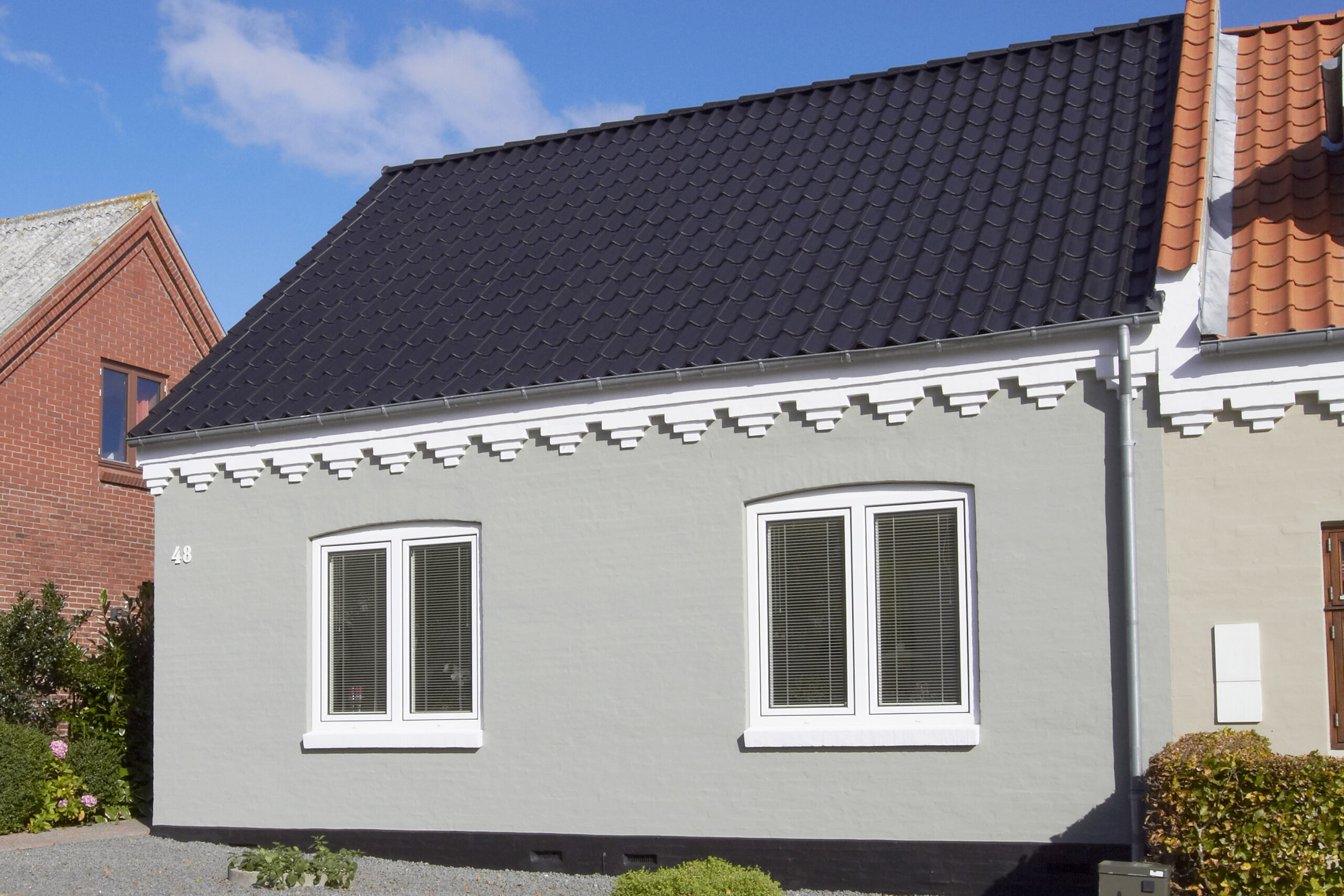 Gråt hus med sort tegltag og hvide vinduer