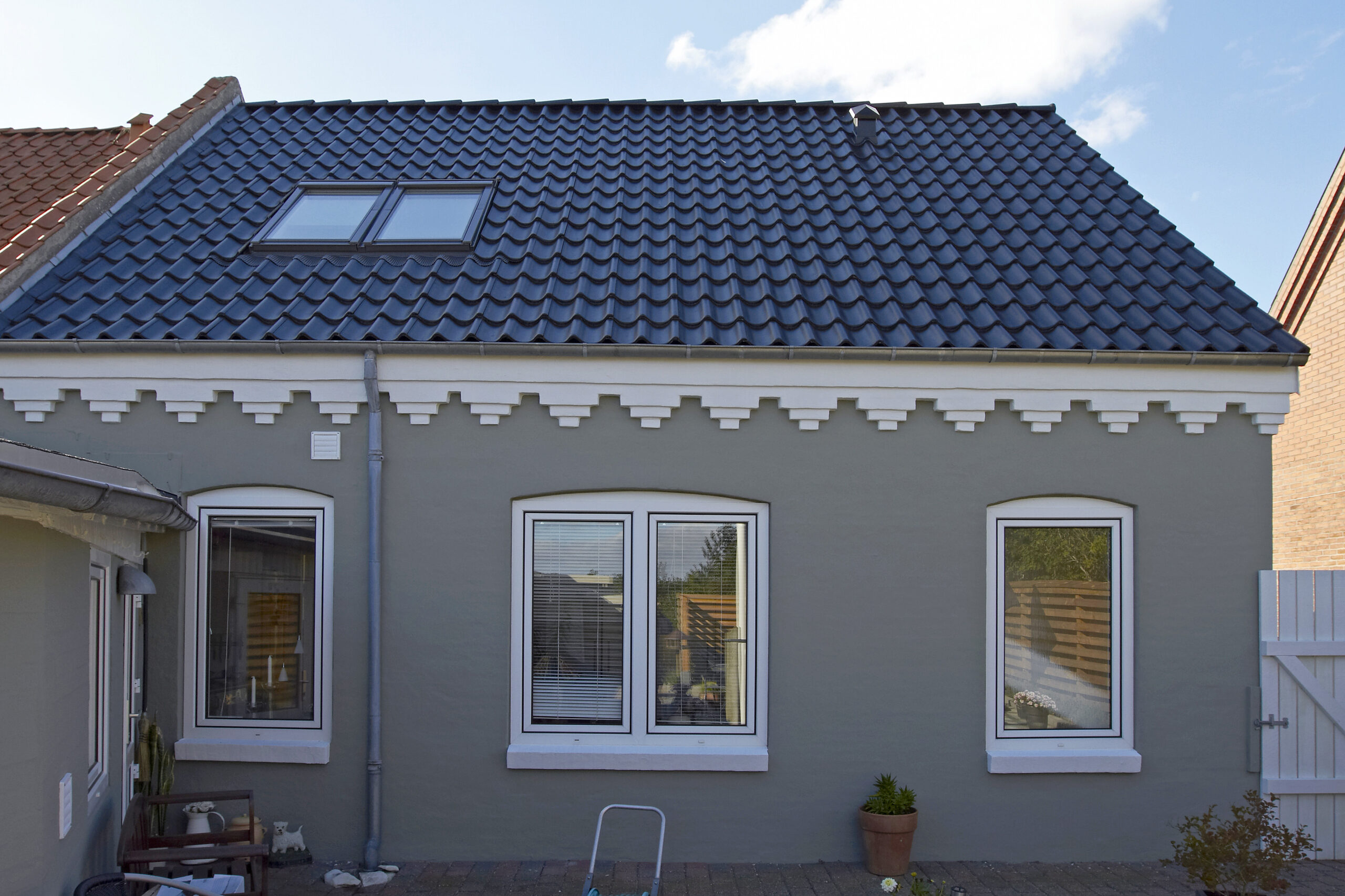 Gråt hus med blåt tegltag og ovenlysvinduer