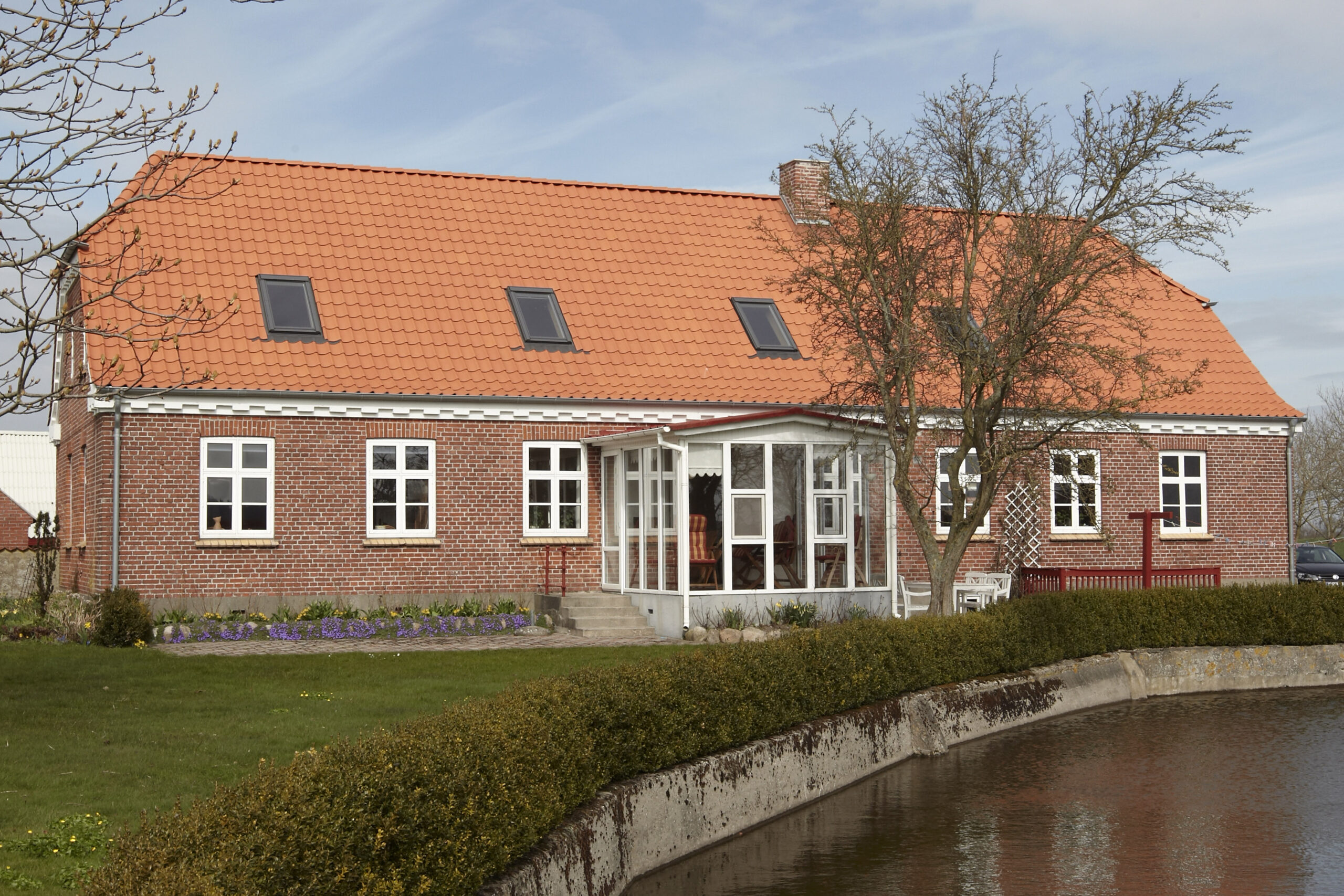 Rødstenshus med tegltag ved kanal
