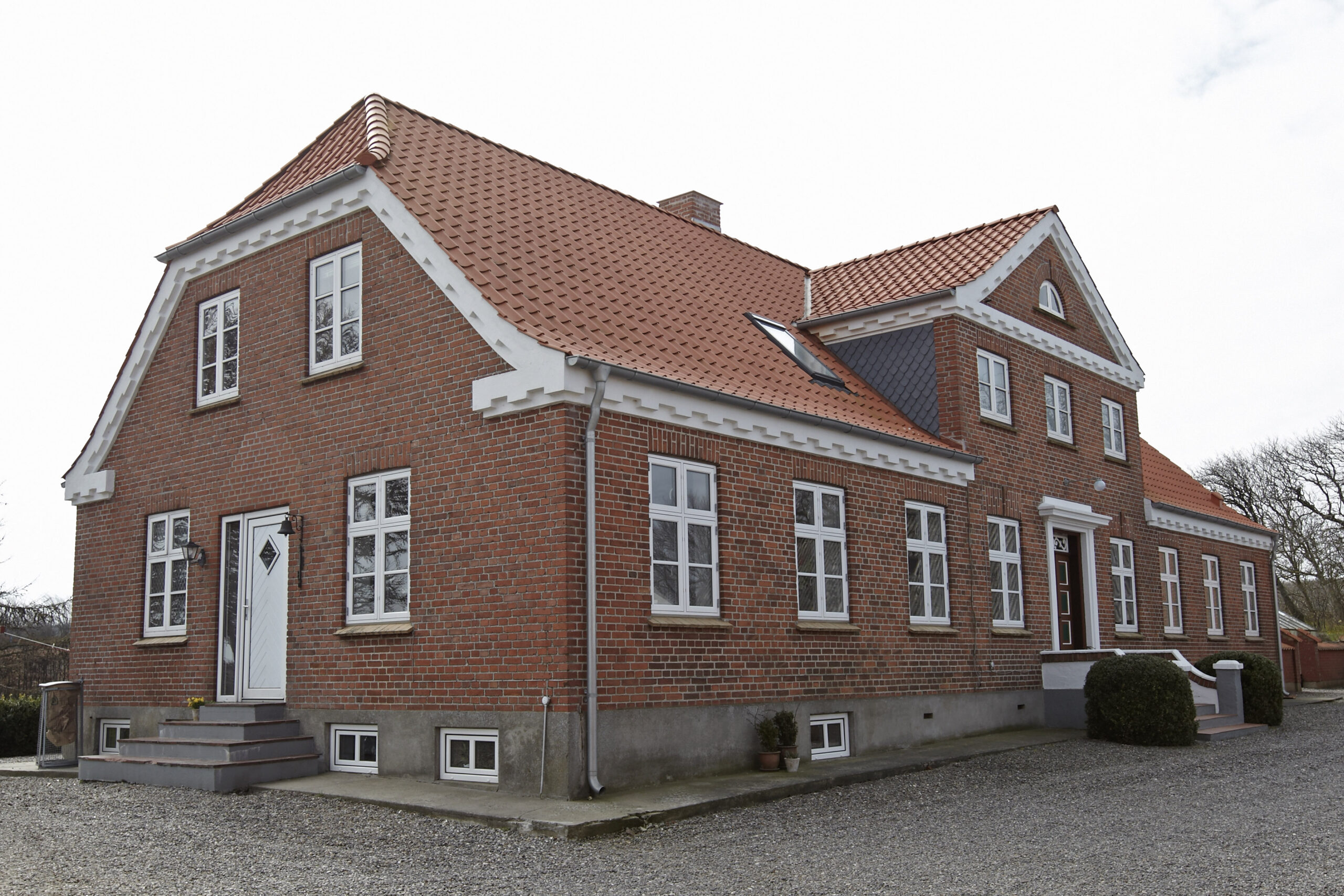 Rødstensvilla med tegltag og hvide vinduer
