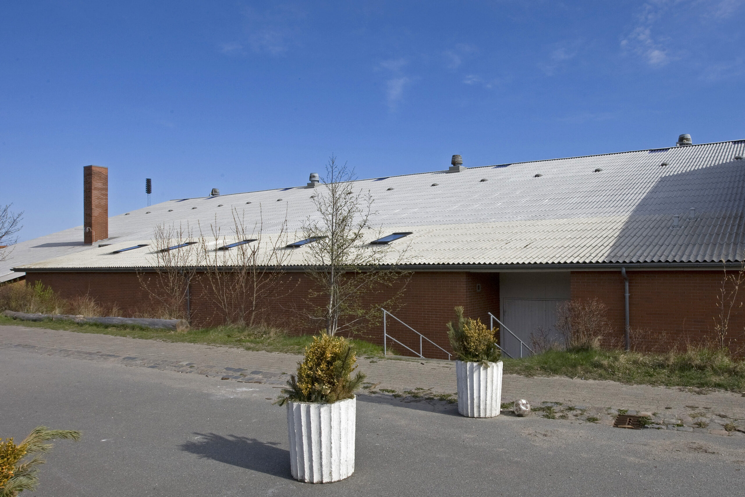 Lang rød murstensbygning med lyst tag