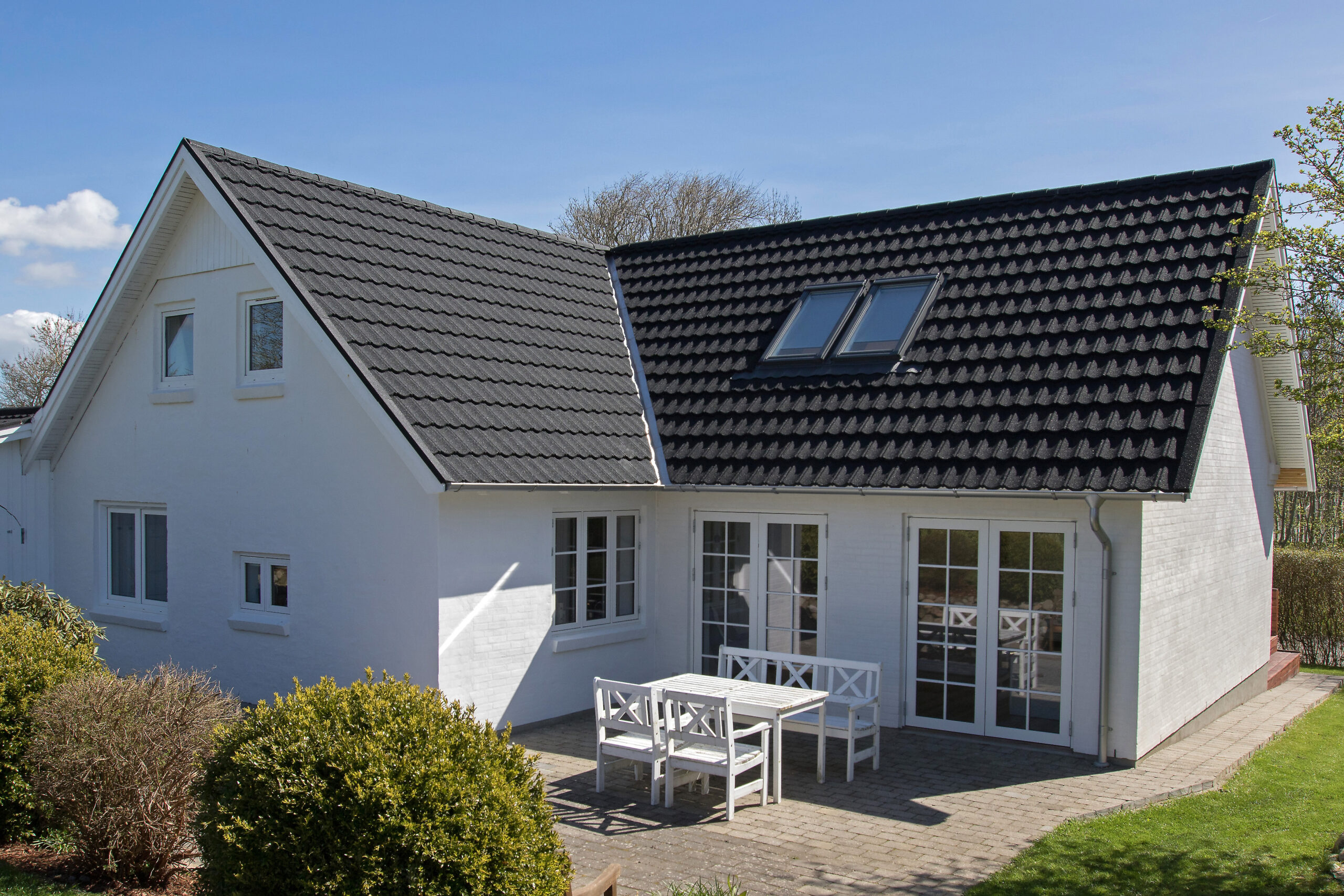 Hvidt hus med sort tag og terrasse