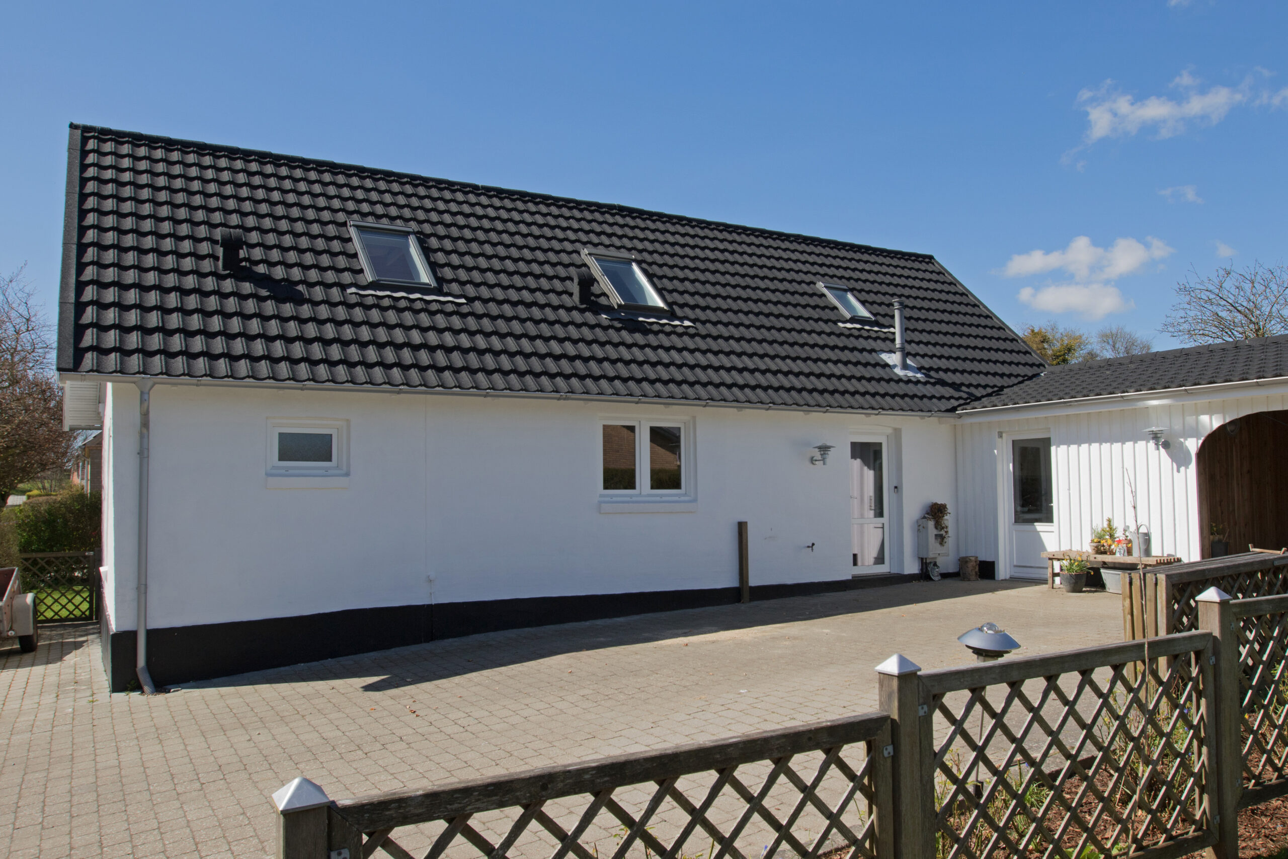 Hvid villa med sort tegltag og ovenlysvinduer