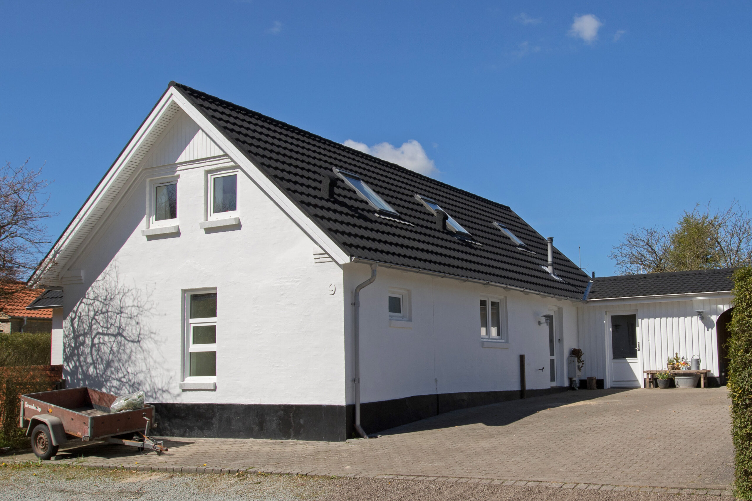 Hvidt hus med sort tag og indkørsel