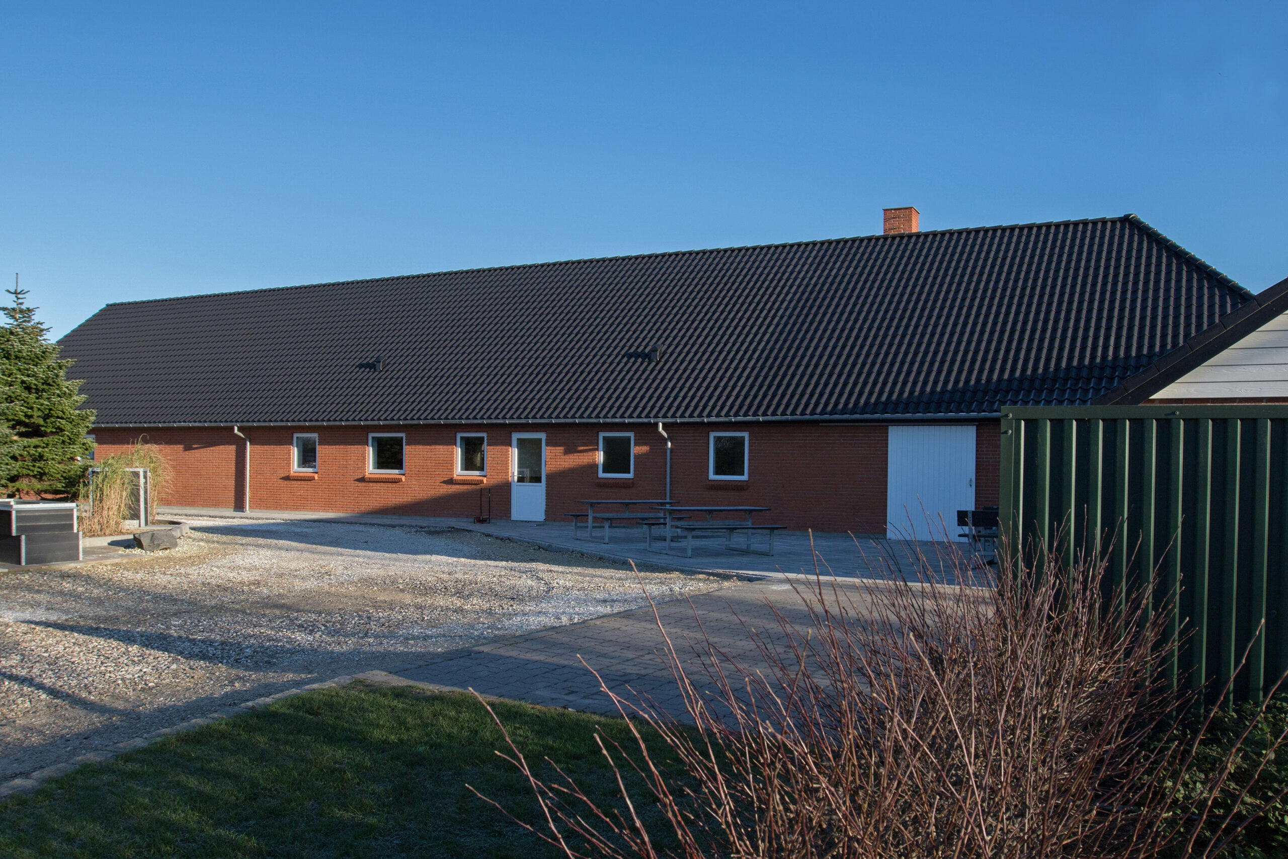 Lang rød murstensbygning med sort tegltag