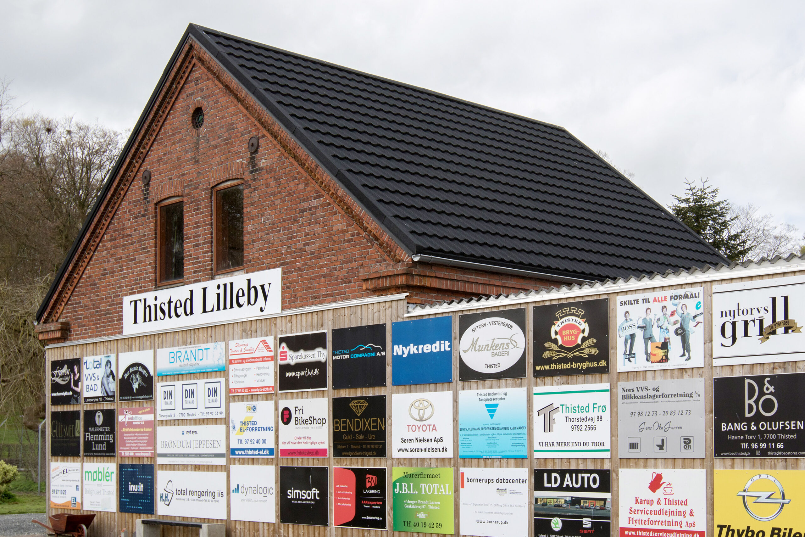 Murstensbygning med skiltet Thisted Lilleby og firmalogoer