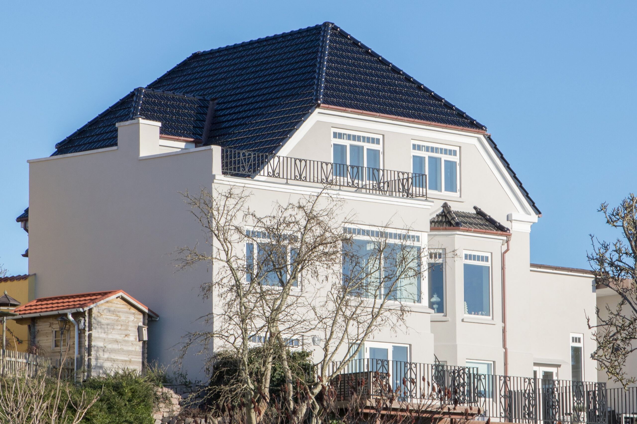Moderne hvid villa med sort tegltag og altaner