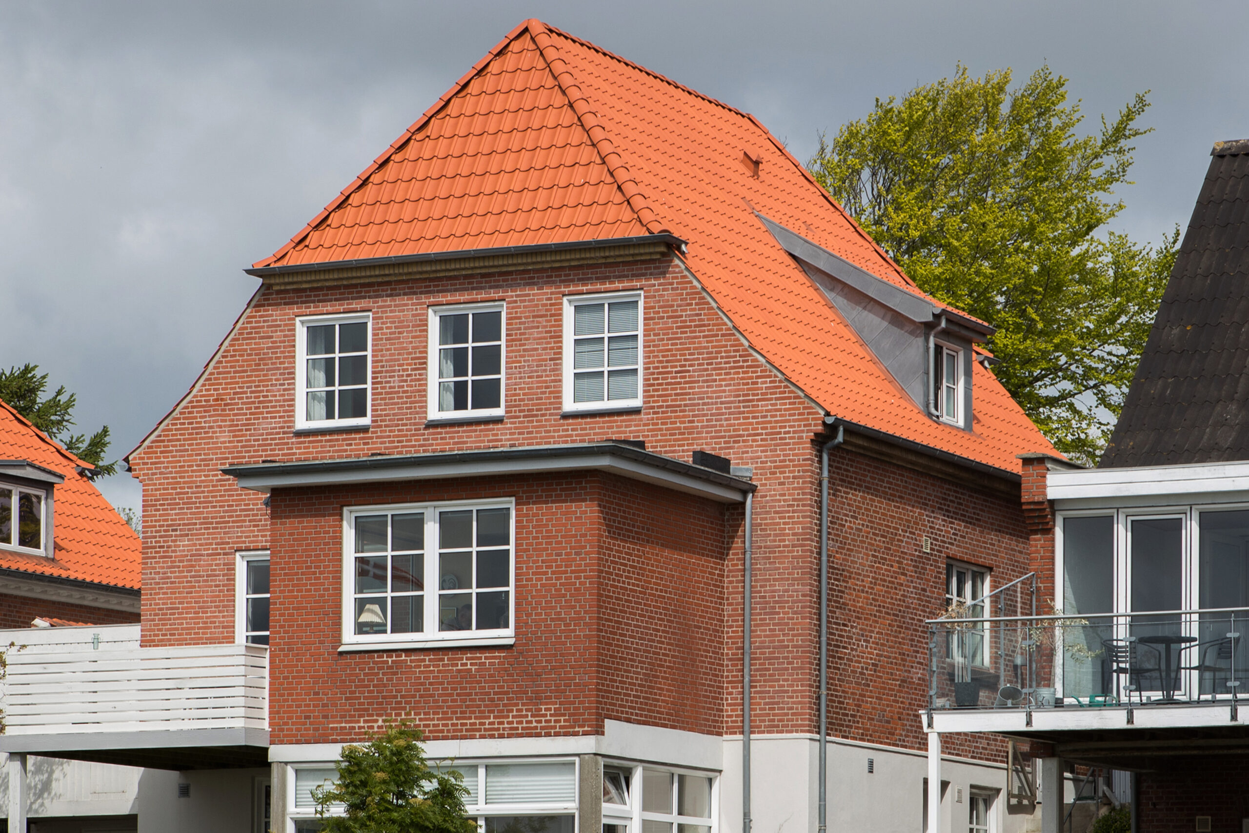 Rødstenshus med orange tegltag og hvide vinduer