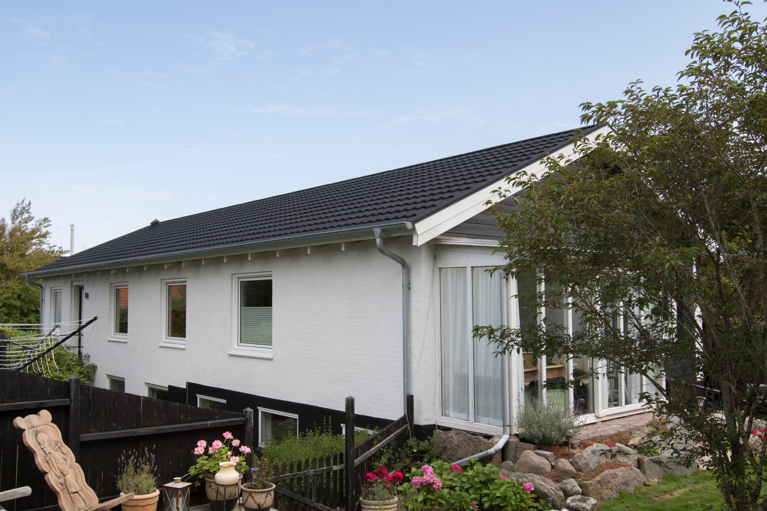 Hvidt hus med sort tag og have