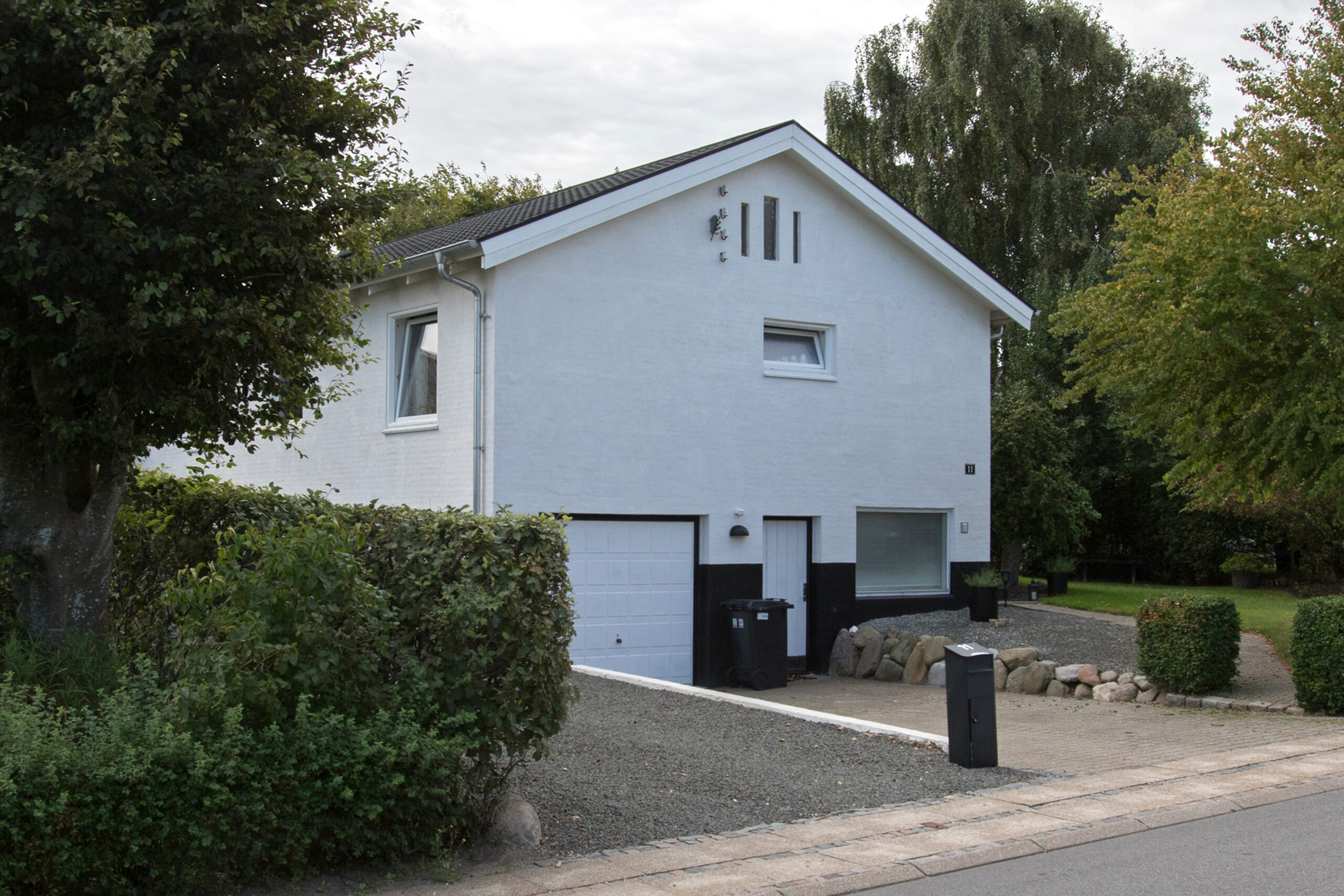 Moderne hvid villa med garage og grusindkørsel