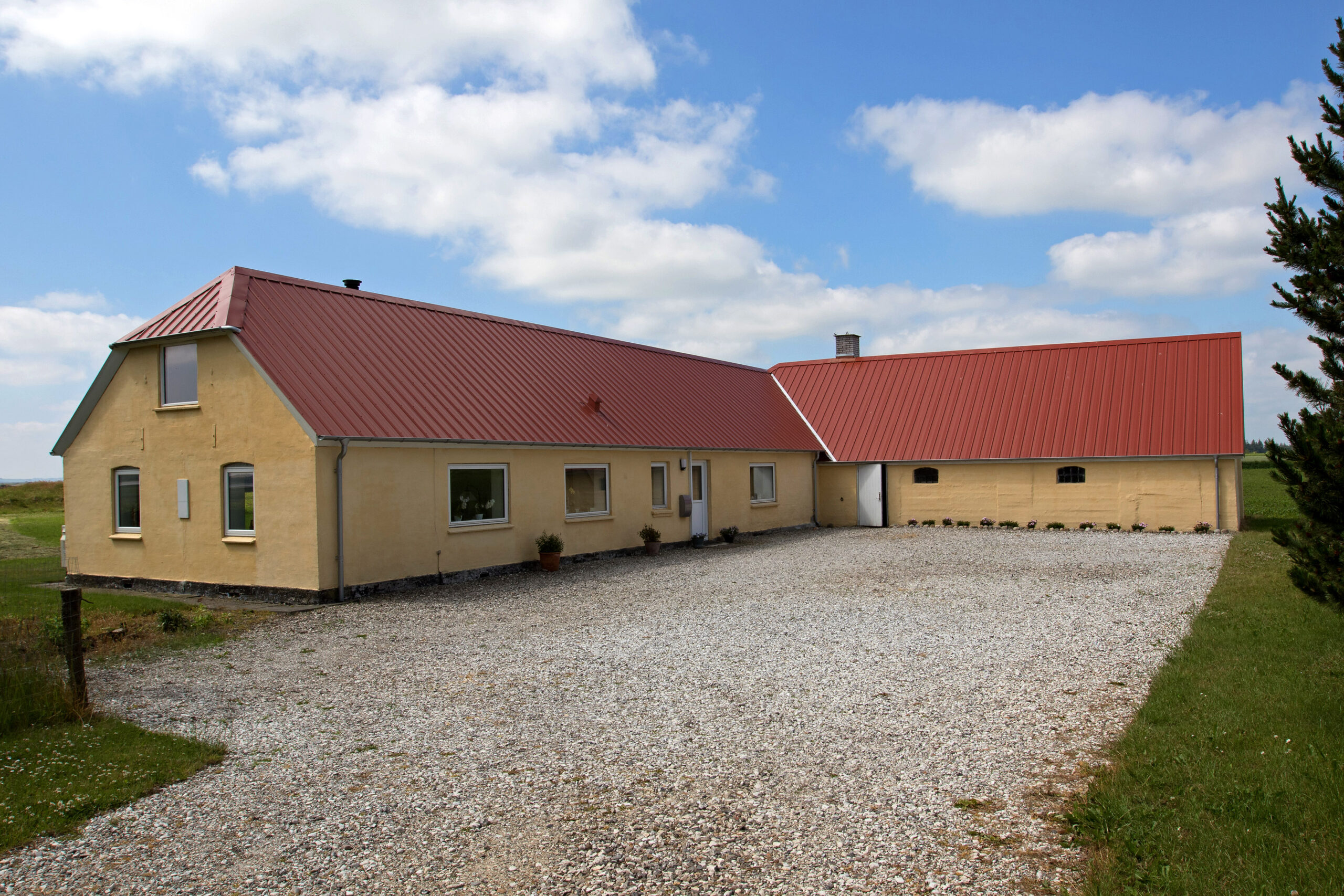 Landhus med rødt tag og grusgård