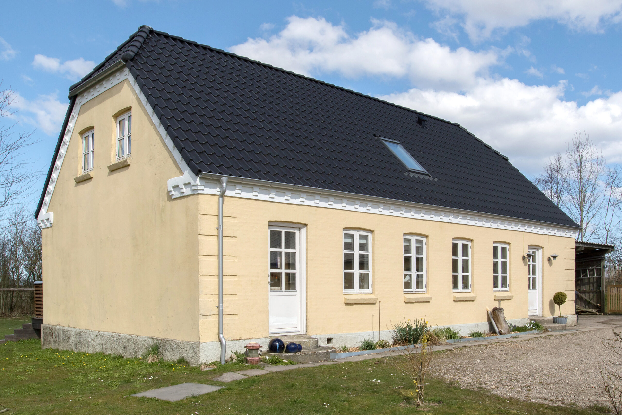 Gult hus med sort tegltag og hvide vinduer