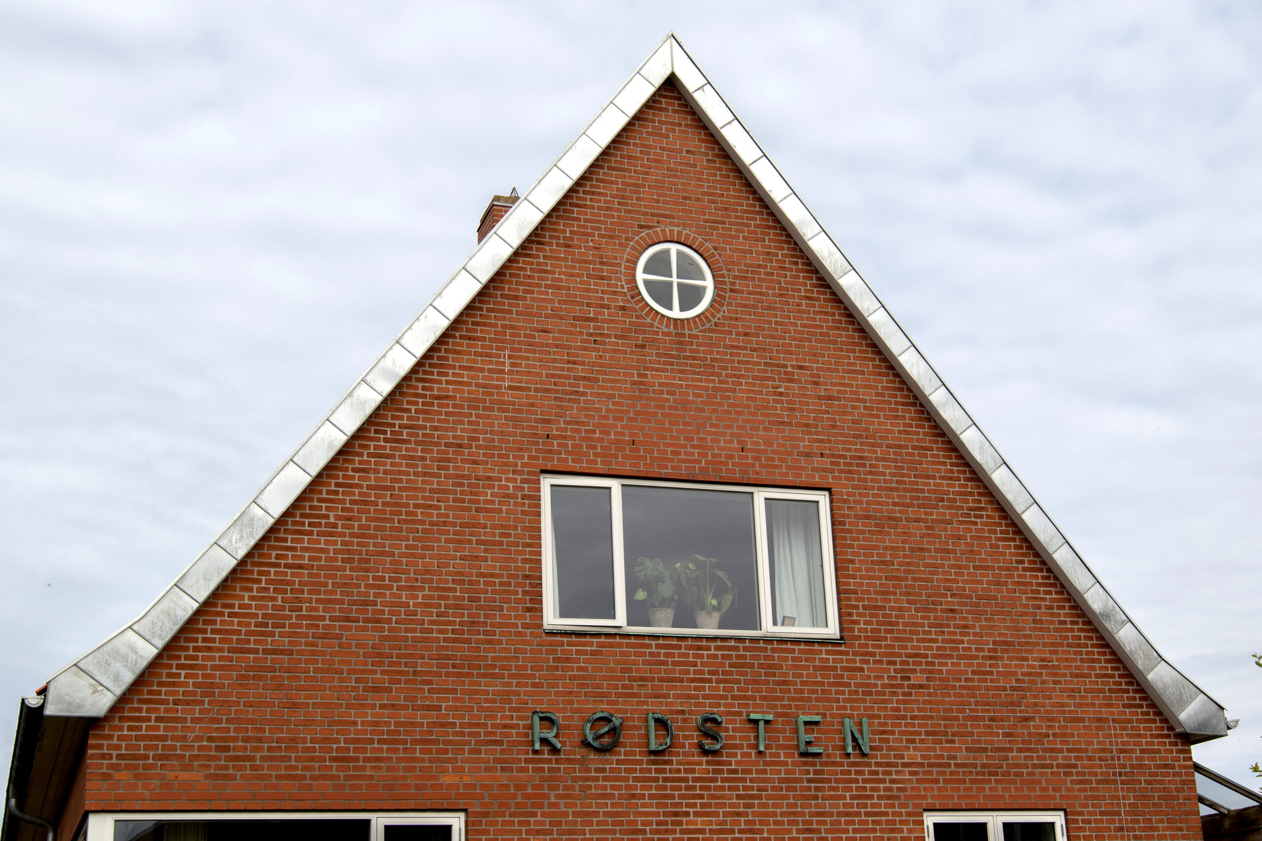 Rød murstensbygning med trekantet gavl og rundt vindue