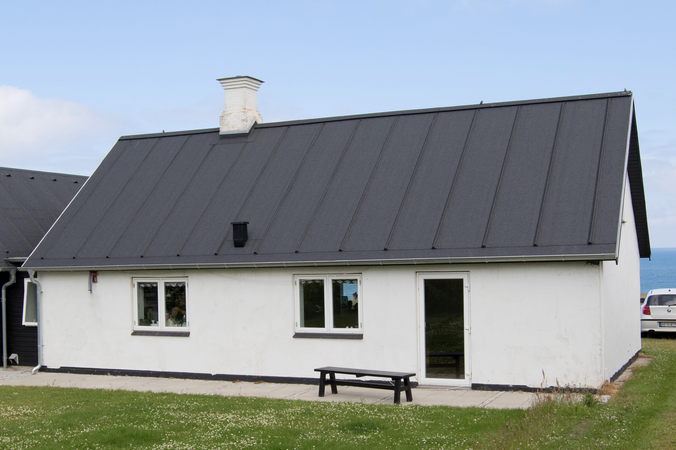 Hvidt hus med sort tag ved havet
