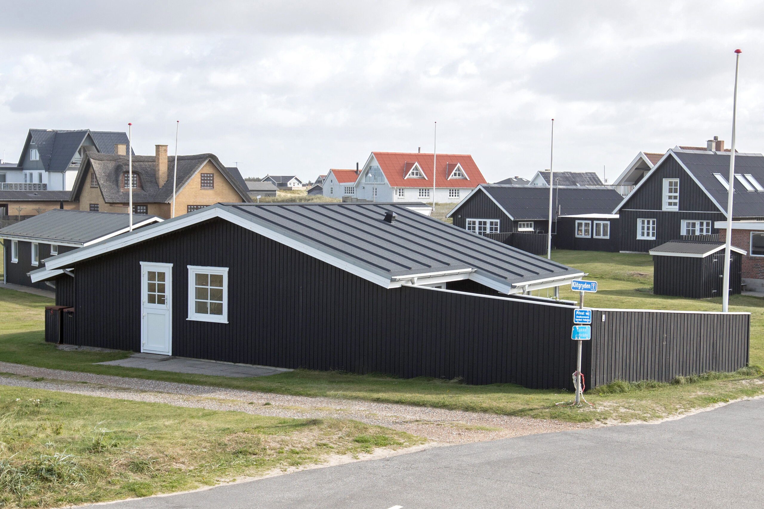 Sort træsommerhus i kystnært boligområde