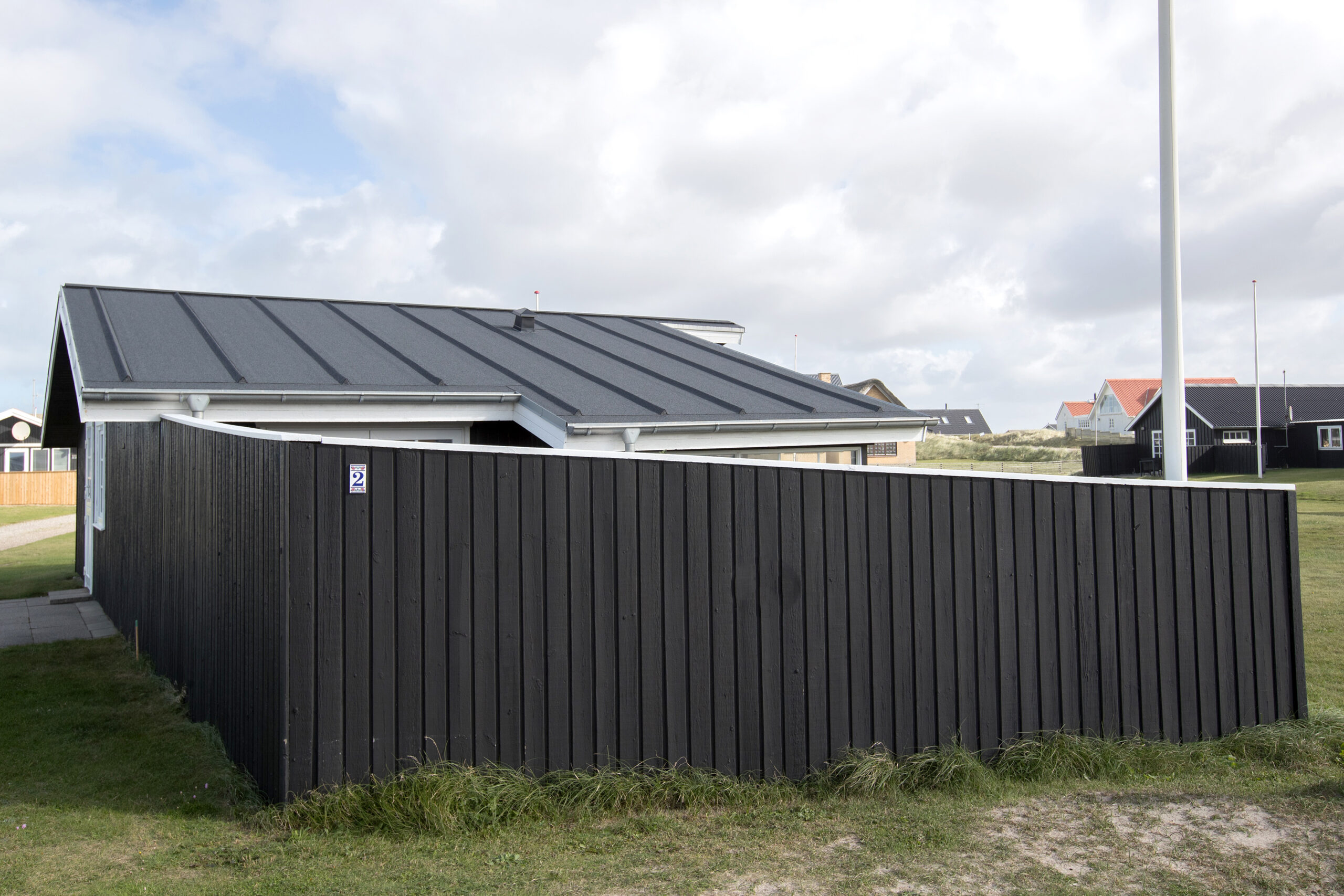 Sort træsommerhus med indhegnet terrasse