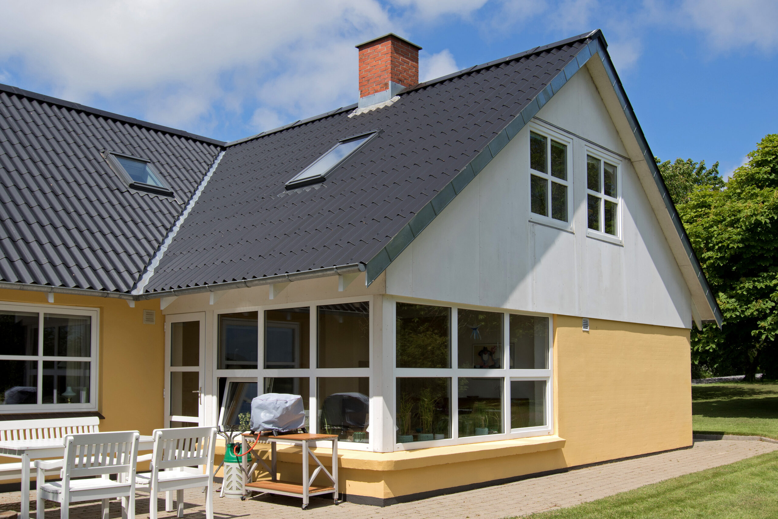 Gult hus med mørkt tag og ovenlysvinduer