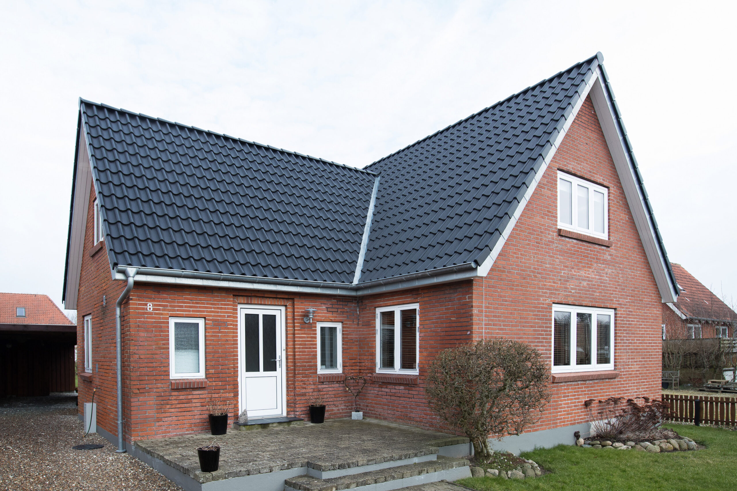 Rødstenshus med sort tegltag og hvid facade