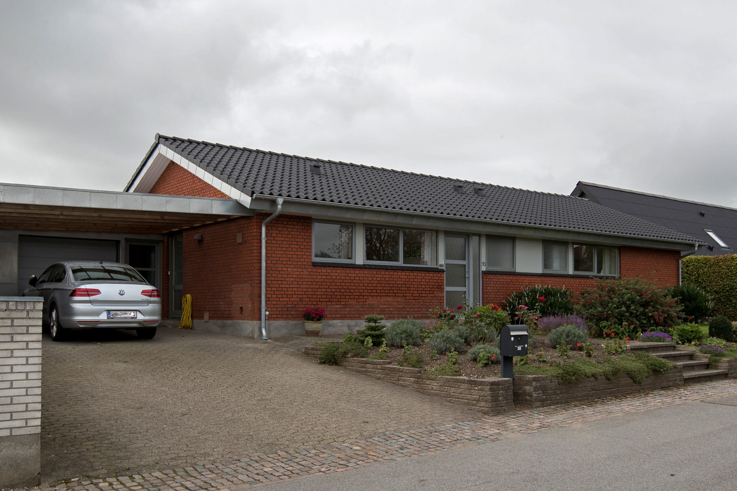 Rødstensvilla med carport og have foran