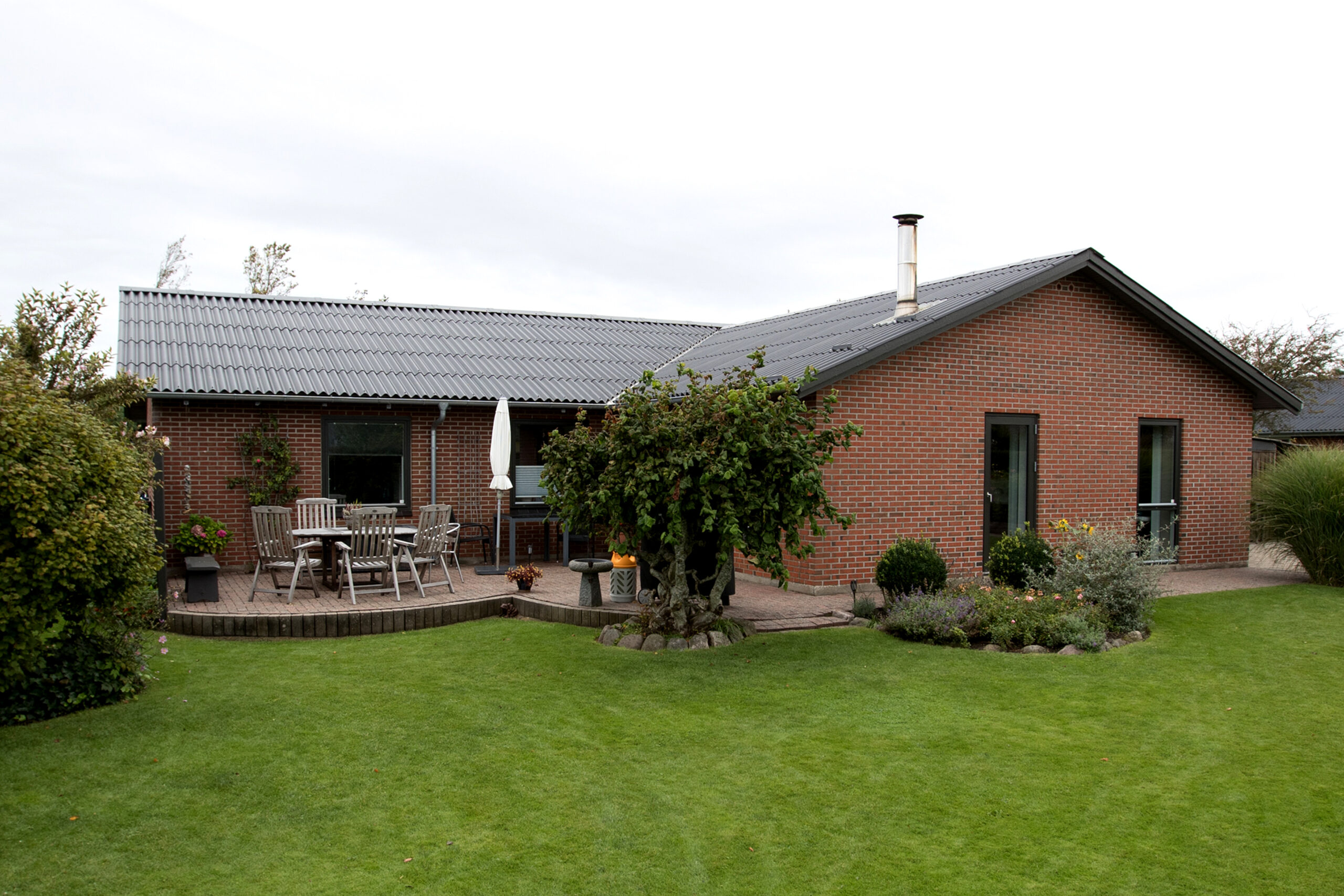Rødstensvilla med terrasse og grøn have