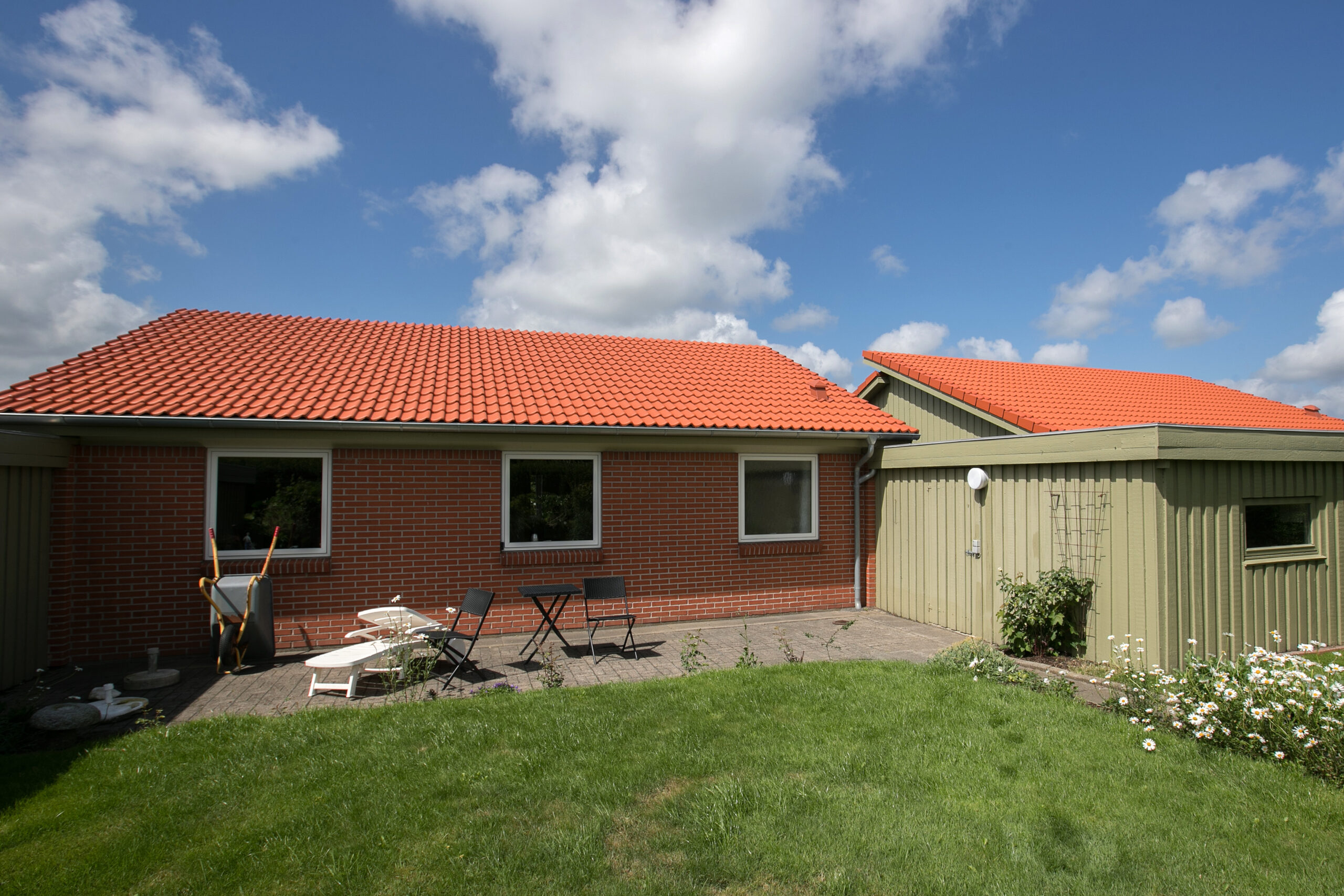 Murstenshus med rød tegltag og terrasse