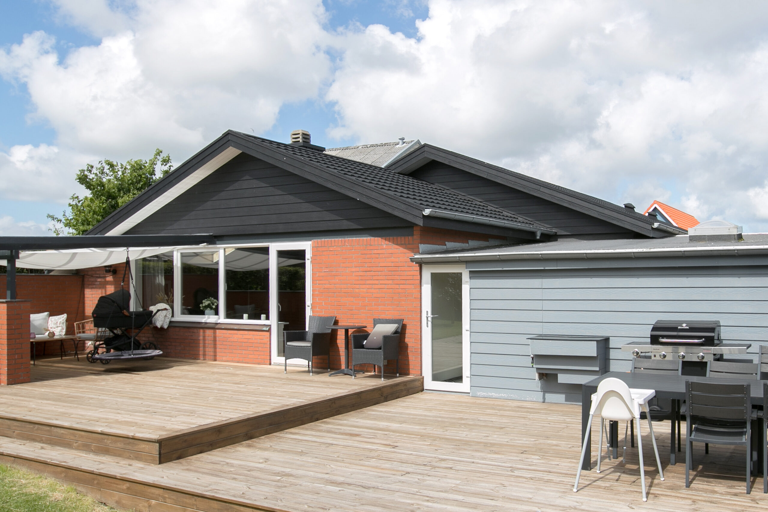 Moderne murstenshus med stor træterrasse og grill