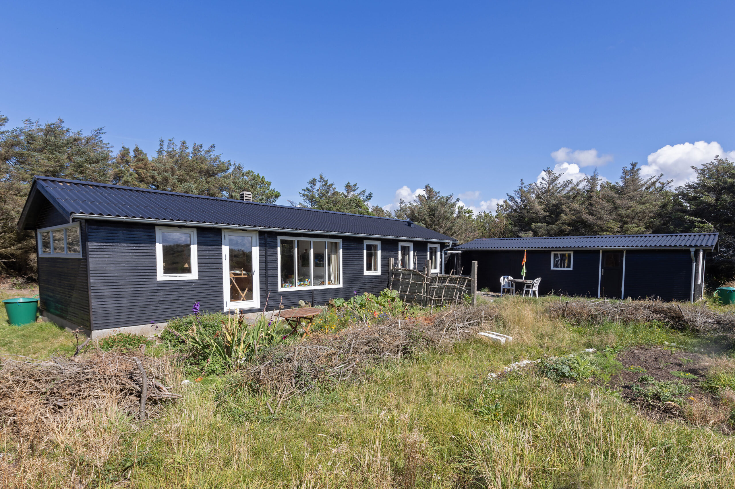 Sort træsommerhus med anneks i naturgrund
