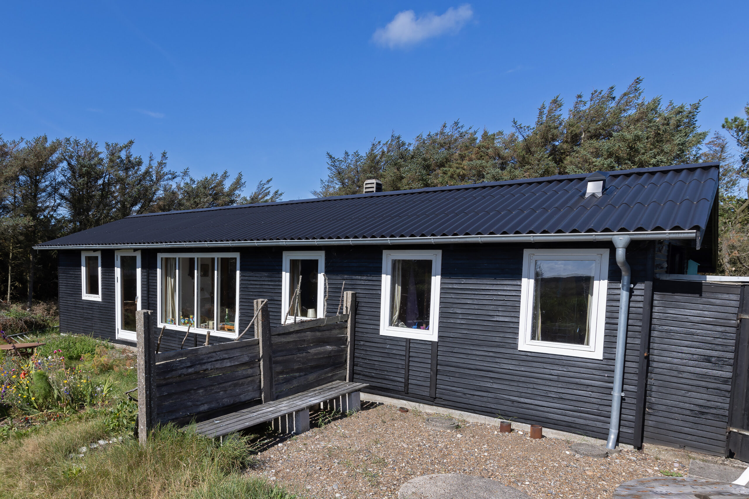 Sort træhus med bølget tag i solskin