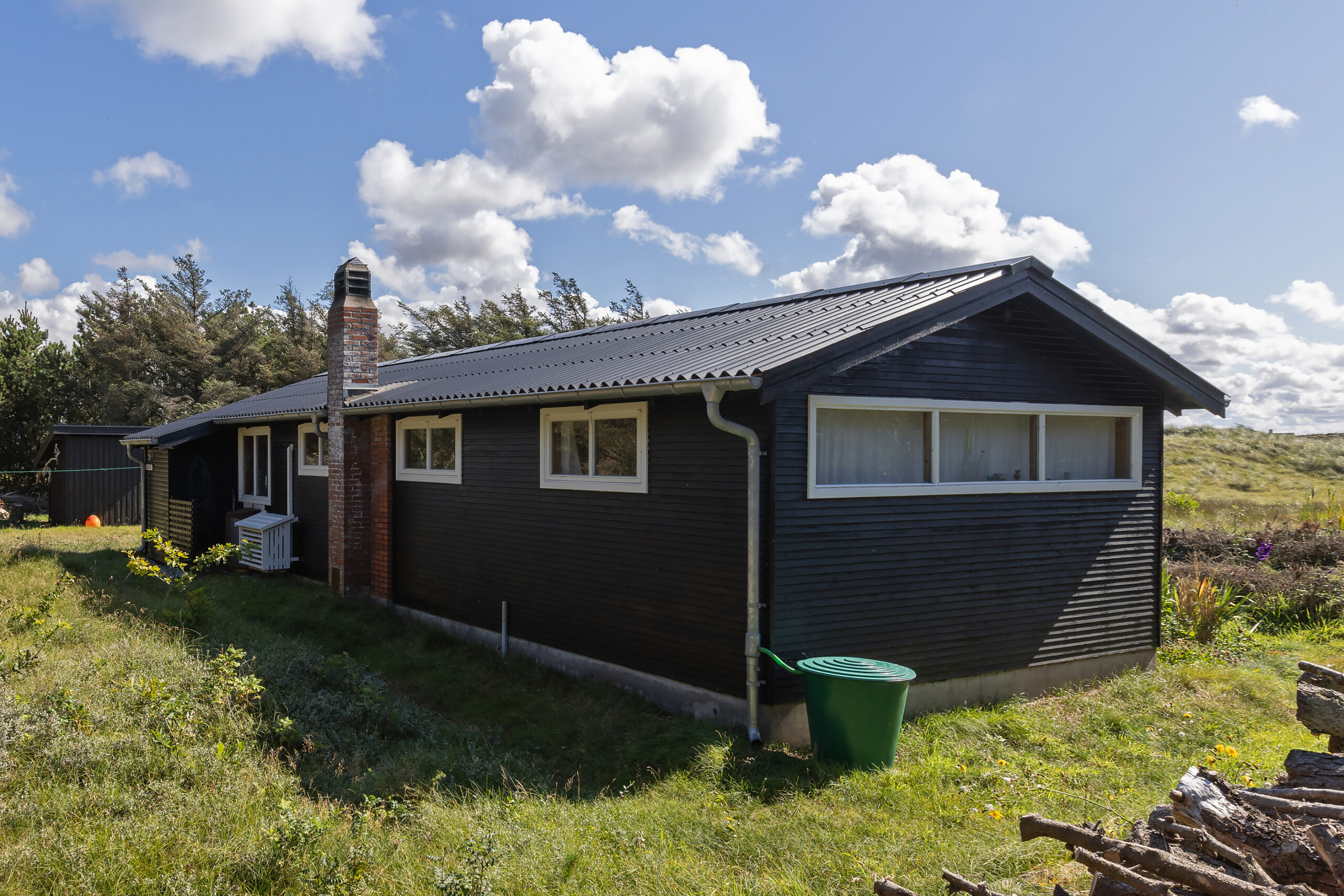 Sort træsommerhus i solrigt landskab