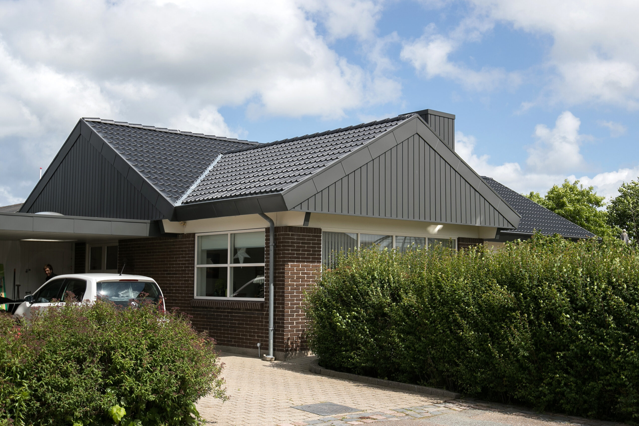Moderne murstenshus med mørkt tegltag og carport
