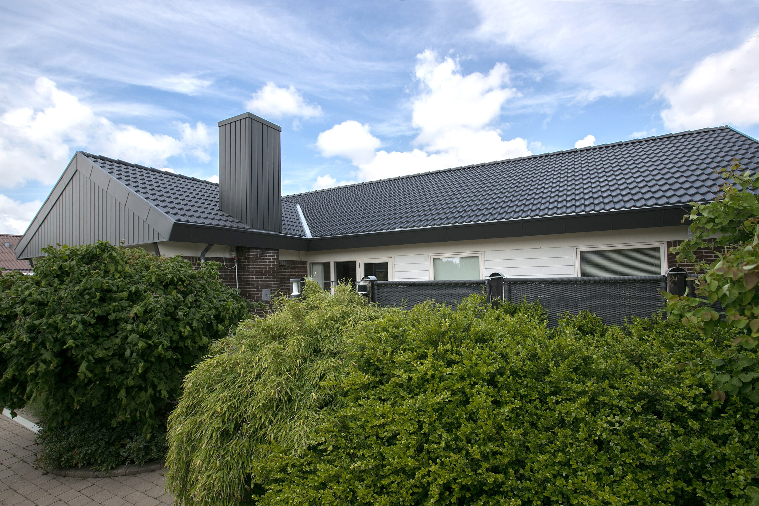 Moderne hus med mørkt tegltag og hæk