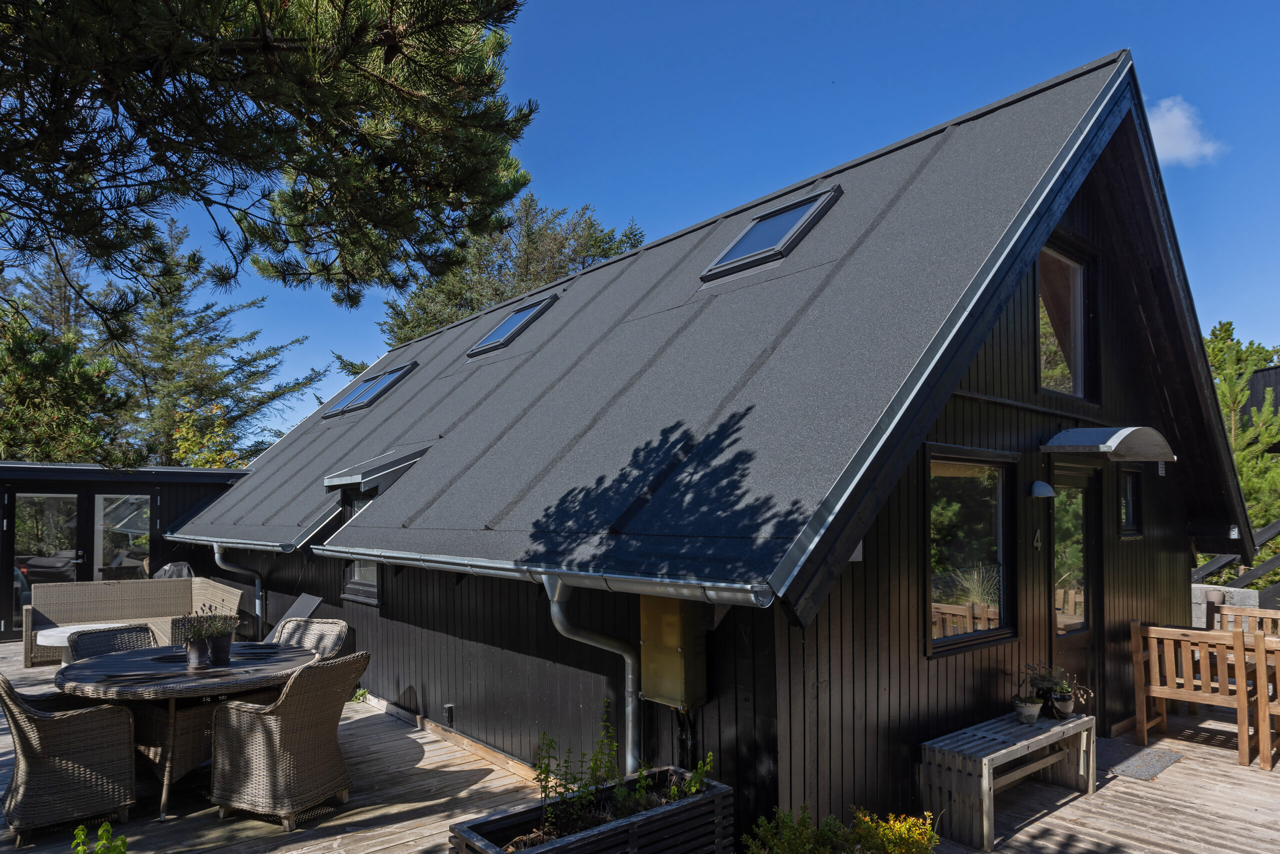 Sort A-formet sommerhus med terrasse og ovenlysvinduer