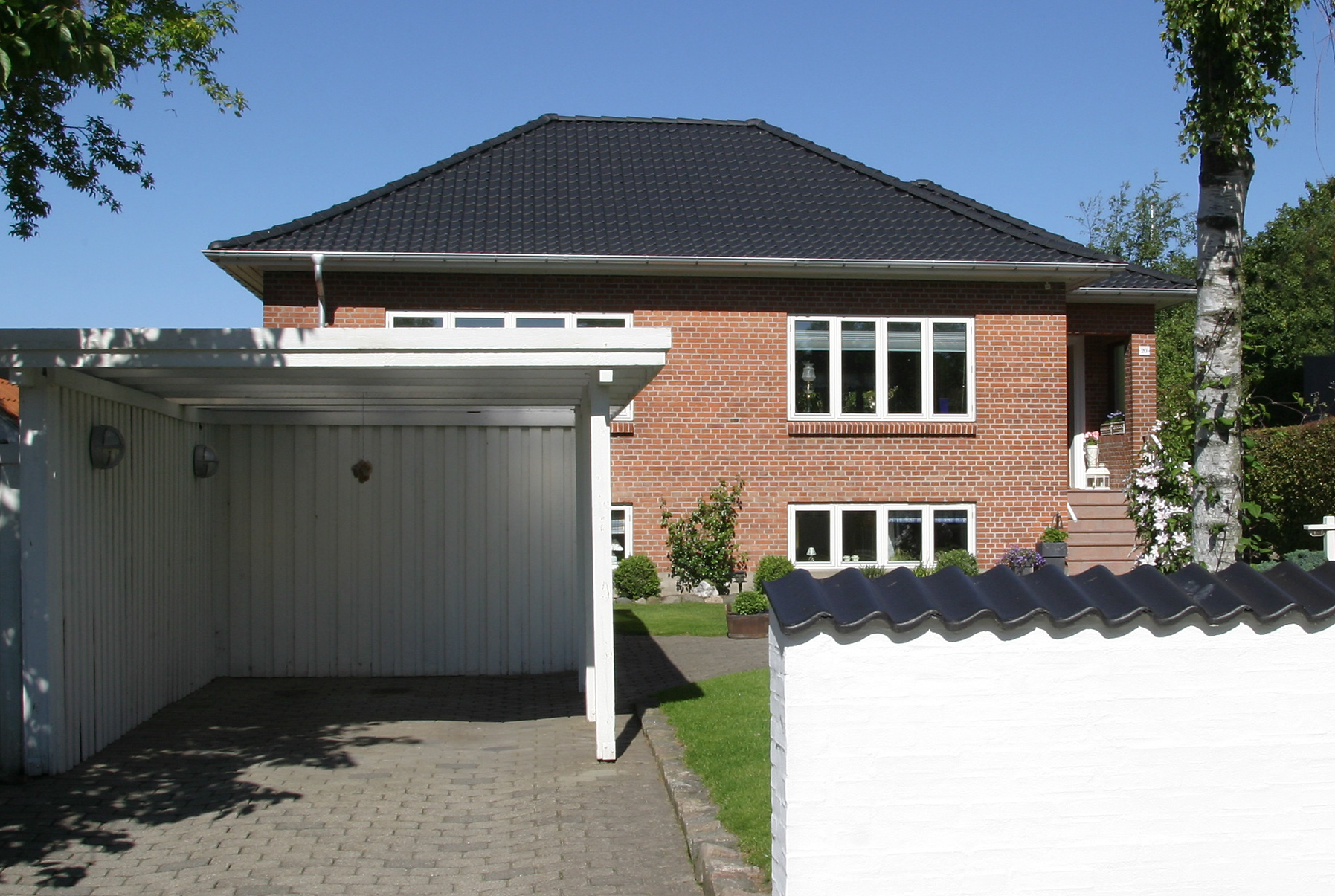 Rødstensvilla med carport og hvid mur