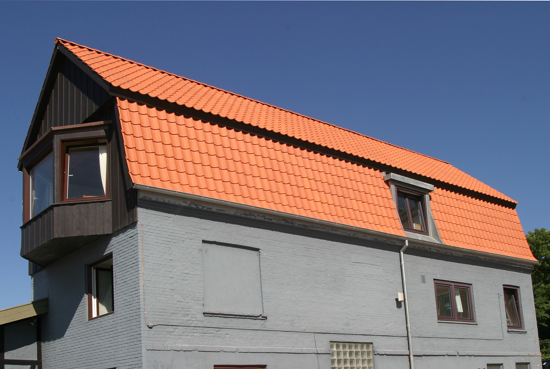 Gråt murstenshus med orange tegltag