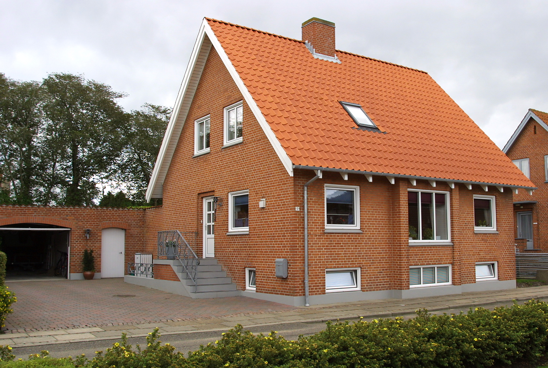 Rødstenshus med orange tegltag og garage