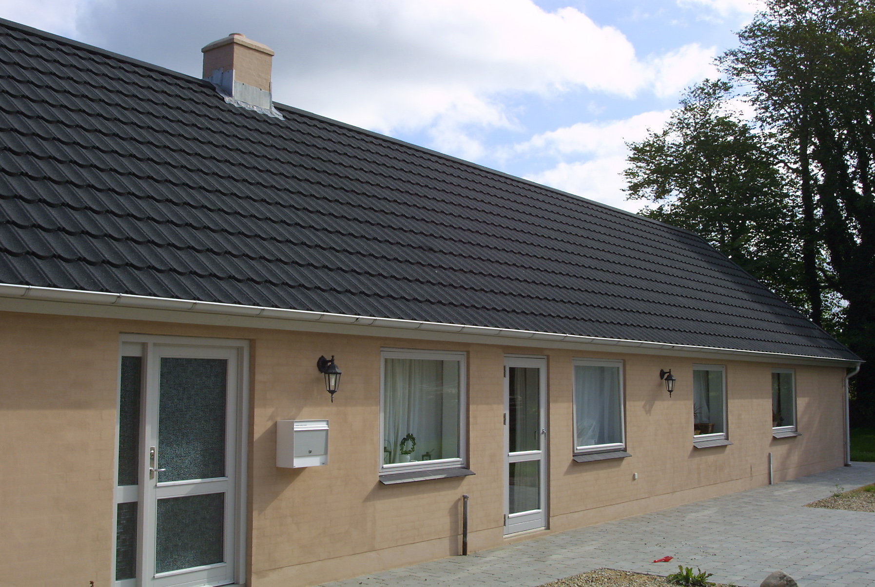 Enetplanshus med mørkt tegltag og beige facade