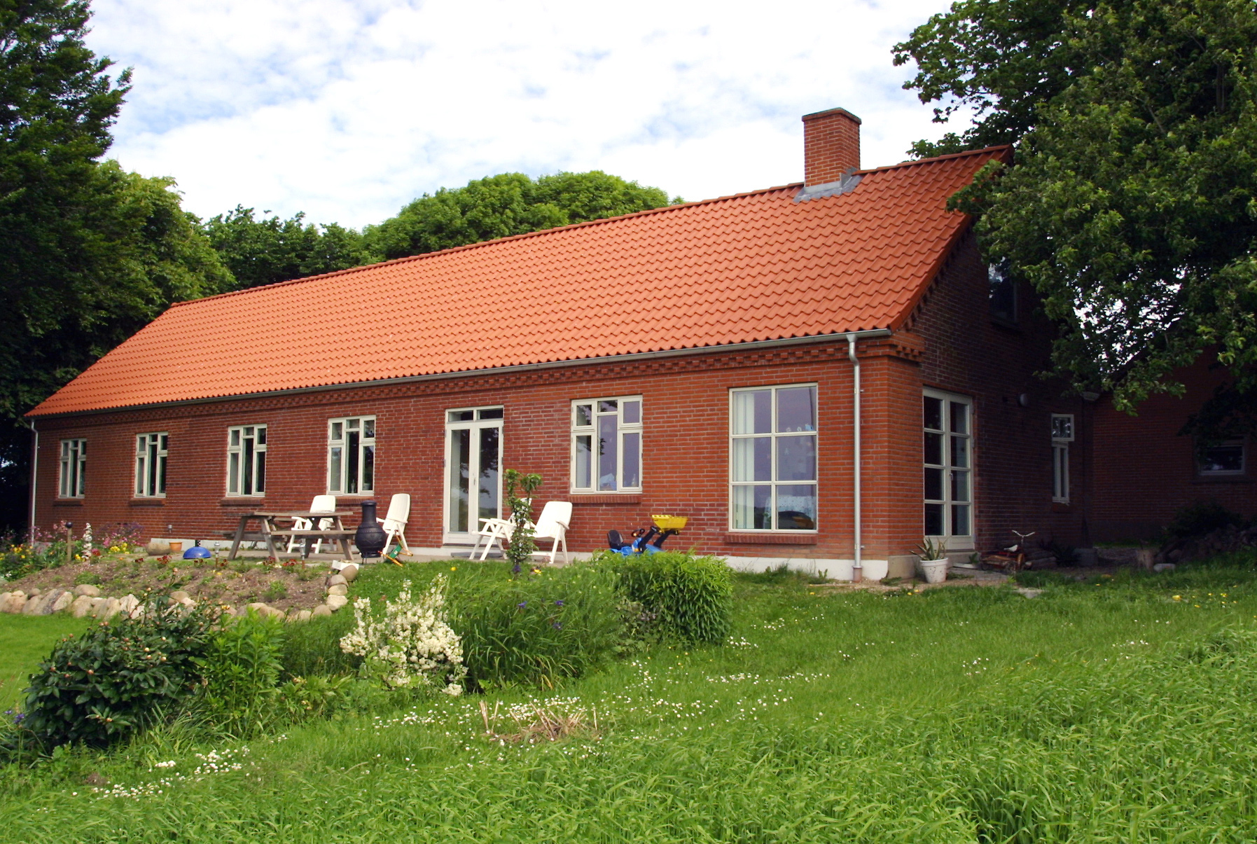 Rødstenshus med tegltag og grøn have