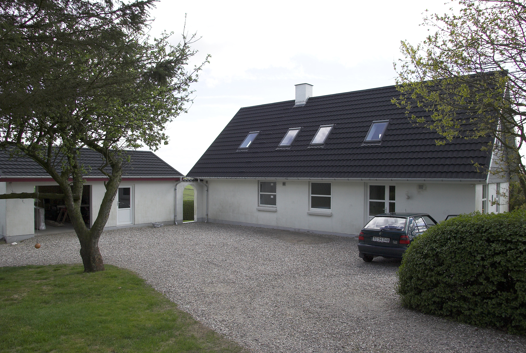 Hvid villa med sort tag og grusindkørsel