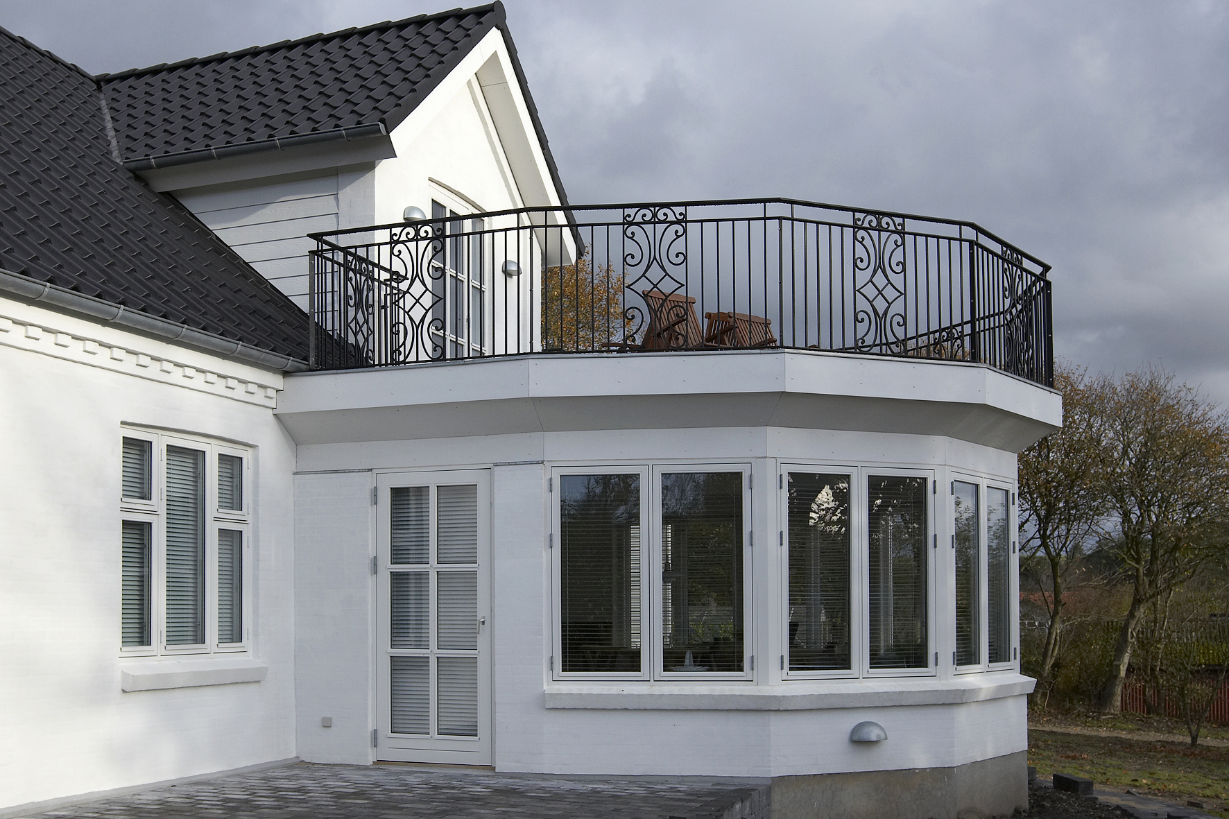 Hvid villa med balkon og sort tag