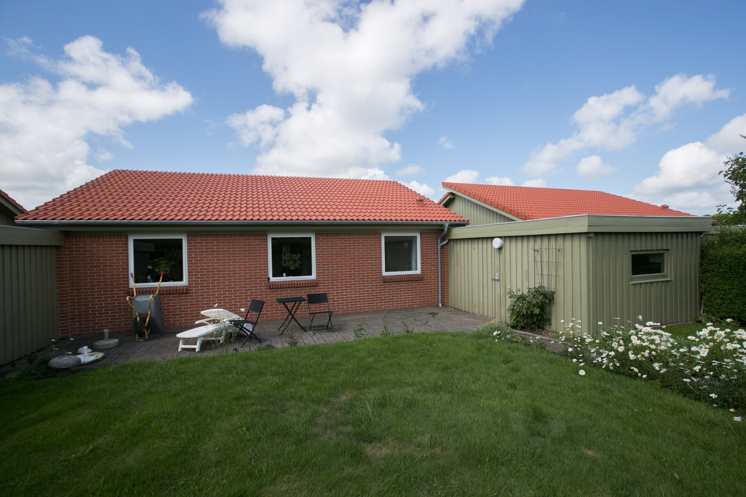 Murstenhus med rødtag og lille terrasse